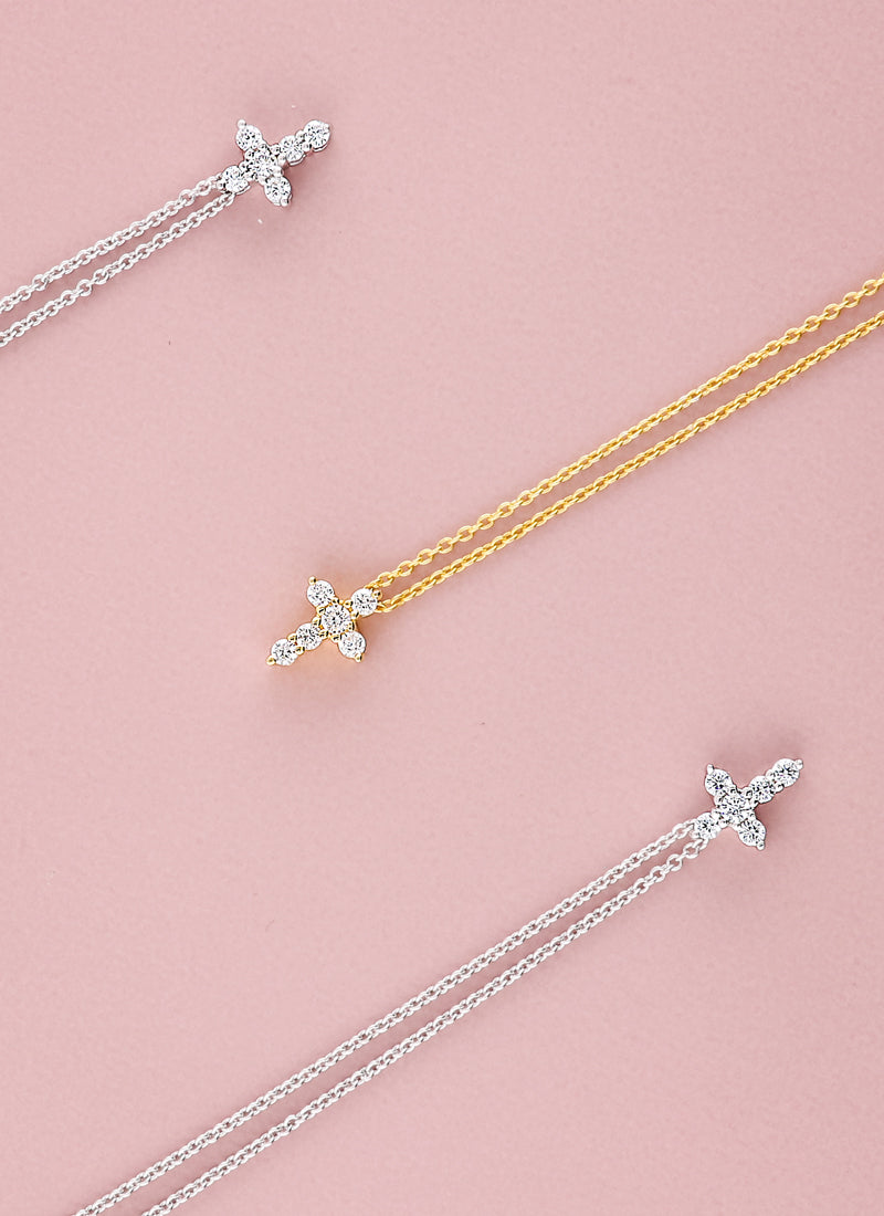 assorted mini cross necklaces on a pink background