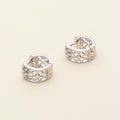 Flatlay view of Clover CZ Small Huggie Earrings in Sterling Silver 0.55 inch, Rhodium Plated