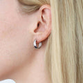 Model wearing Oval Dome Medium Huggie Earrings in Sterling Silver 0.63 inch, Yellow Gold Flashed